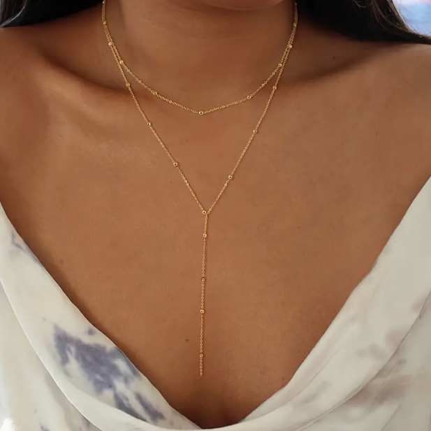 Collier double couche avec perles et pompons géométriques